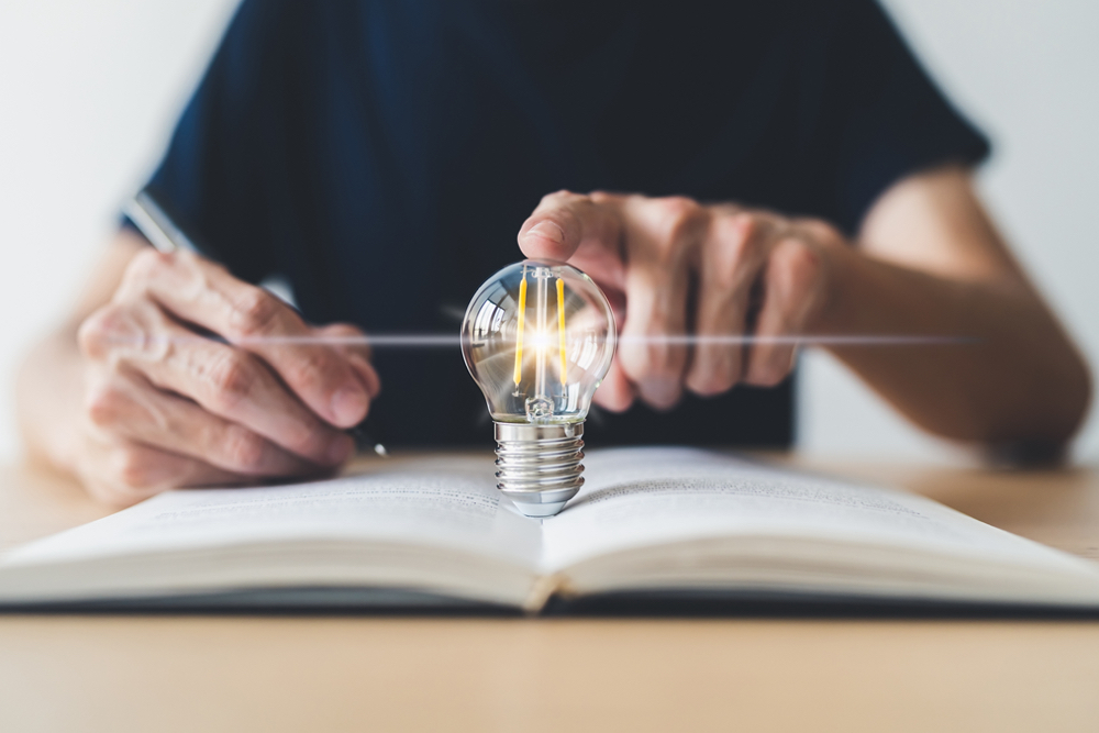 Bright lightbulb or glowing lap with textbook. Business success idea of learning, planning or working.