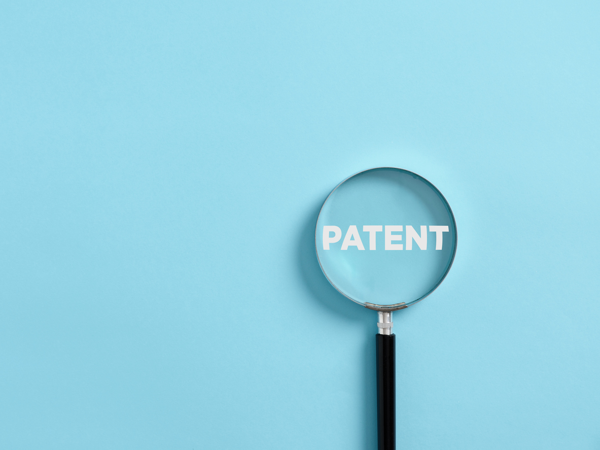 Magnifier focuses on the word patent. Concept of patenting or copyright protection